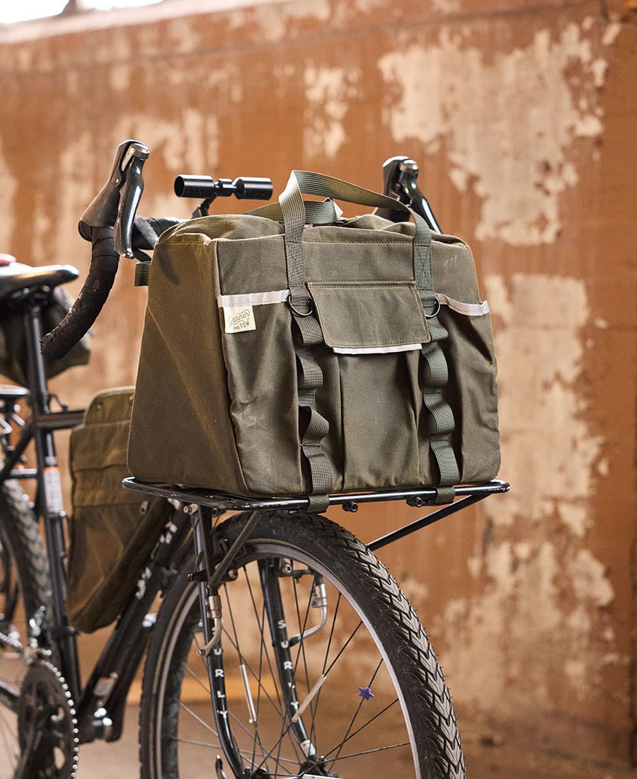 an olive duffel bag on a bike sitting on the front rack
