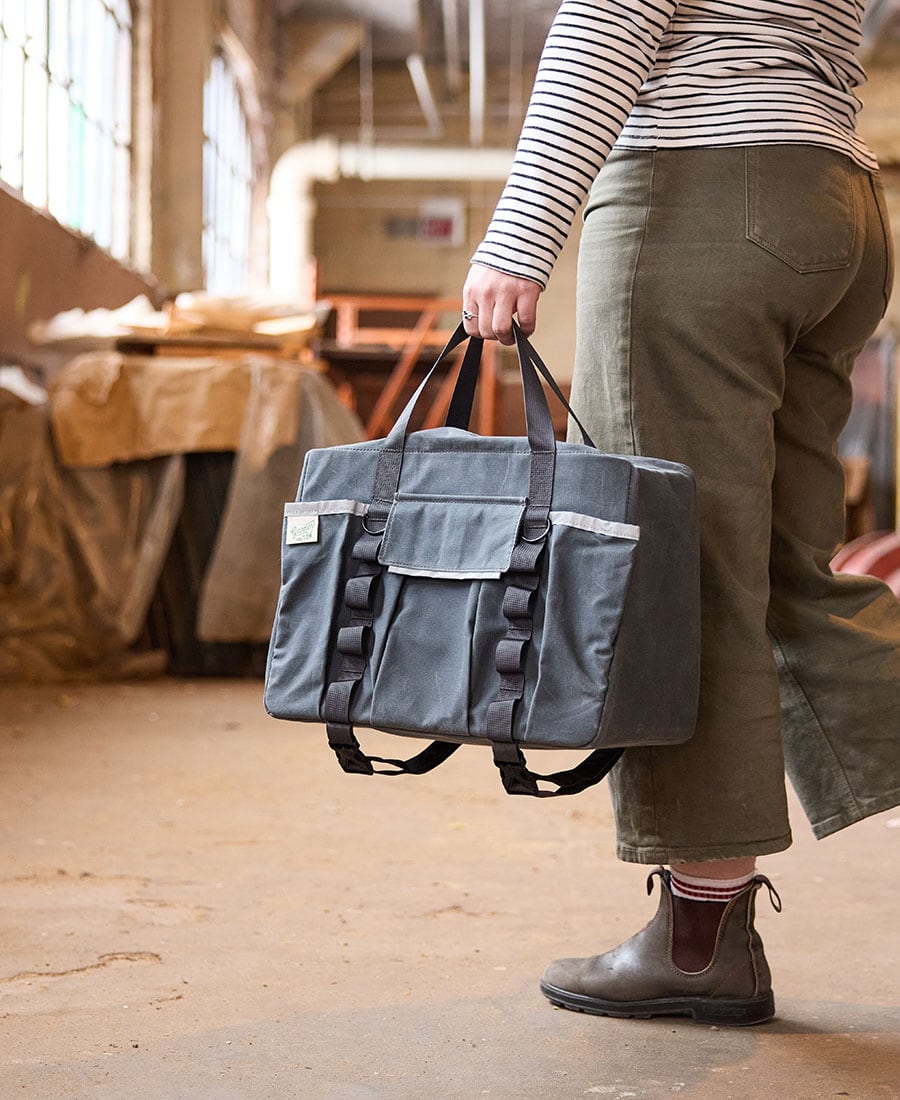 a duffel bag being carried by handle straps by a woman