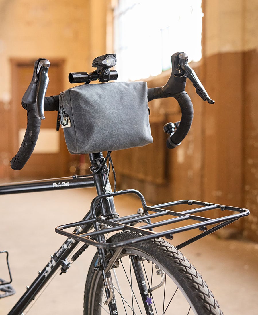a grey fabric pouch attached to the front of a bicycle