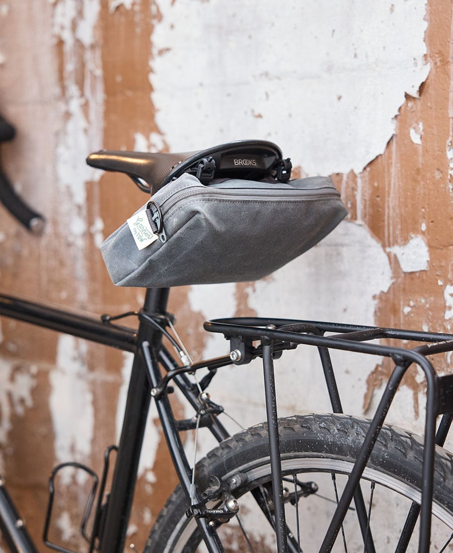 a grey fabric pouch attached to the saddle of a bicycle
