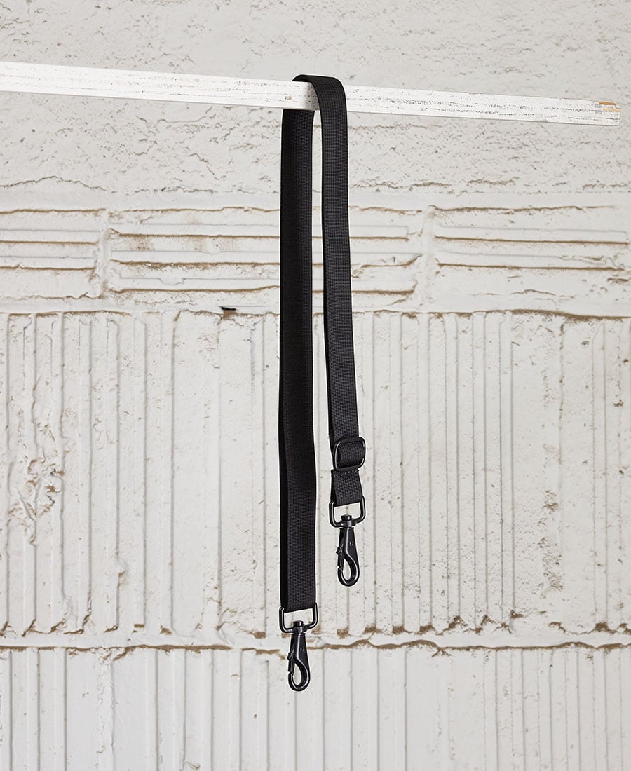 adjustable shoulder strap in black color, with metal snap hooks, displayed parallel to each other against a wooden background.