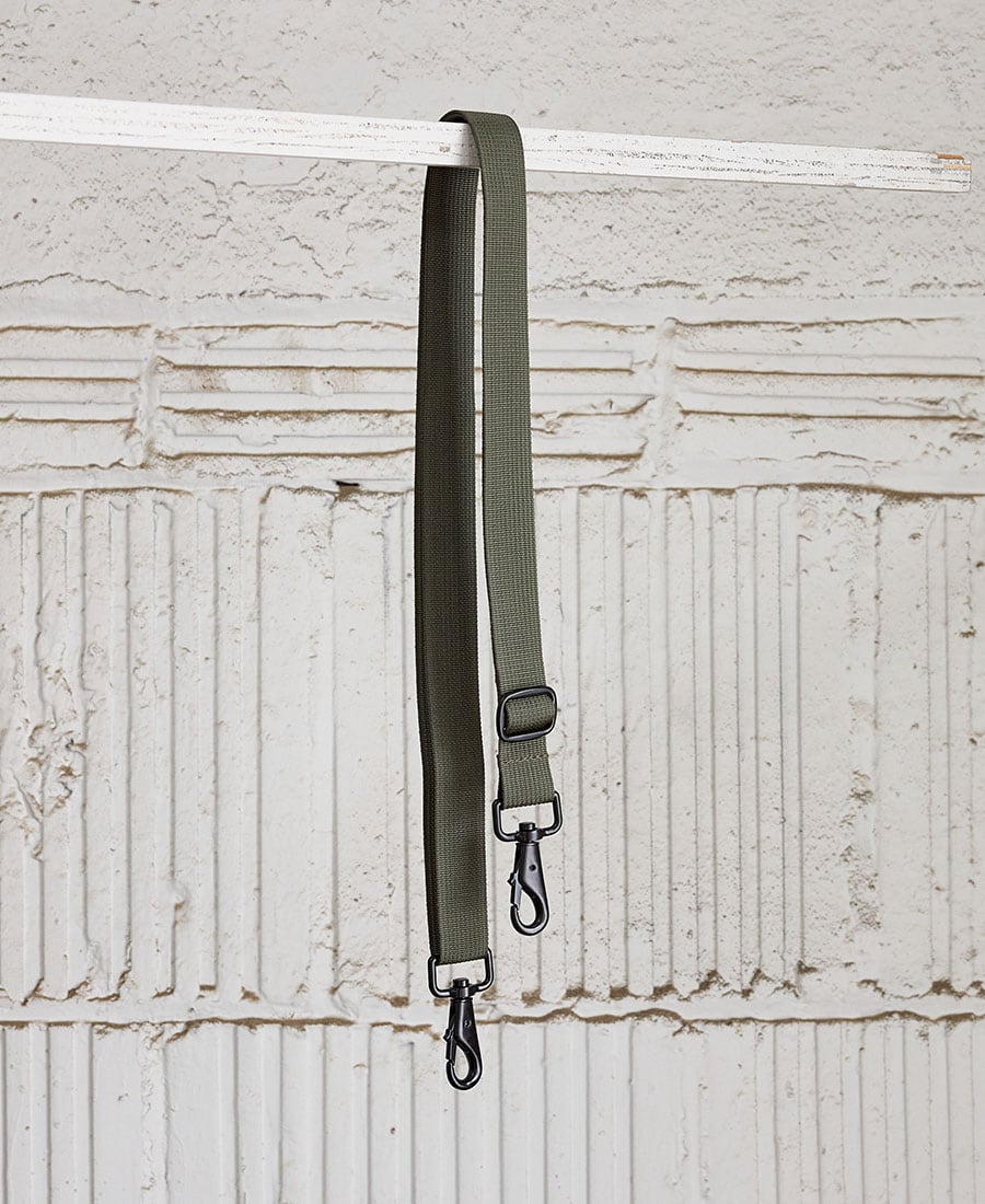 adjustable shoulder strap in green color, with metal snap hooks, displayed parallel to each other against a wooden background.