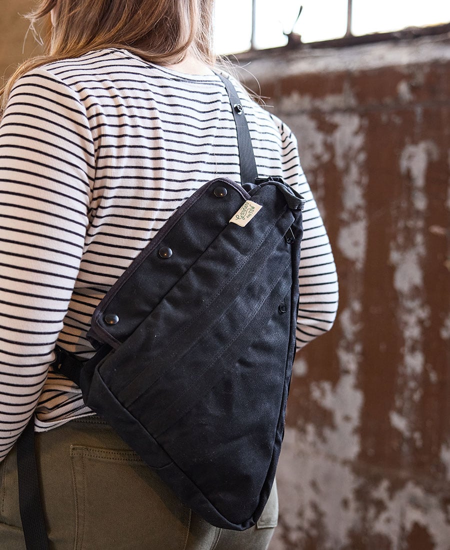a black frame bag being shown as a crossbody sling worn on a woman