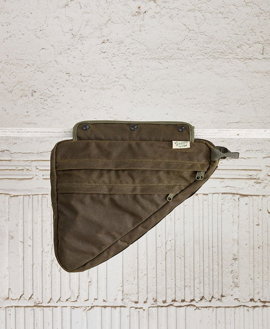 A green bike frame bag made of waxed canvas, with snap closures and an adjustable shoulder strap, displayed against a textured background.