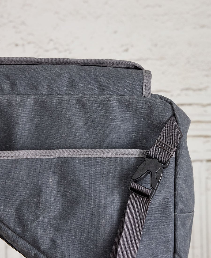 A grey bike frame bag made of waxed canvas, featuring a buckle
