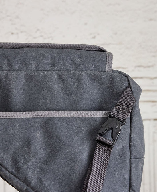 A grey bike frame bag made of waxed canvas, featuring a buckle